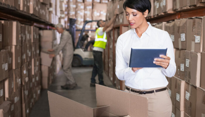 Pretty warehouse manager using tablet pc in a large warehouse